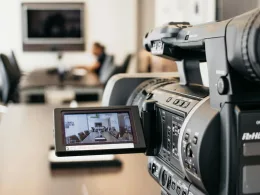 Close-up of professional video camera recording in modern office environment.