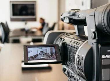 Close-up of professional video camera recording in modern office environment.
