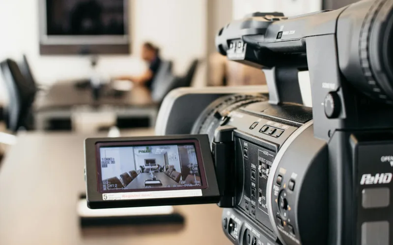 Close-up of professional video camera recording in modern office environment.