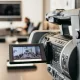 Close-up of professional video camera recording in modern office environment.
