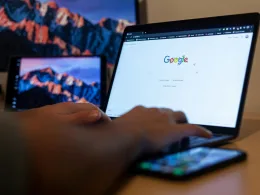 Hands typing on a laptop with Google on screen, in a remote work setup in Milan, Italy.