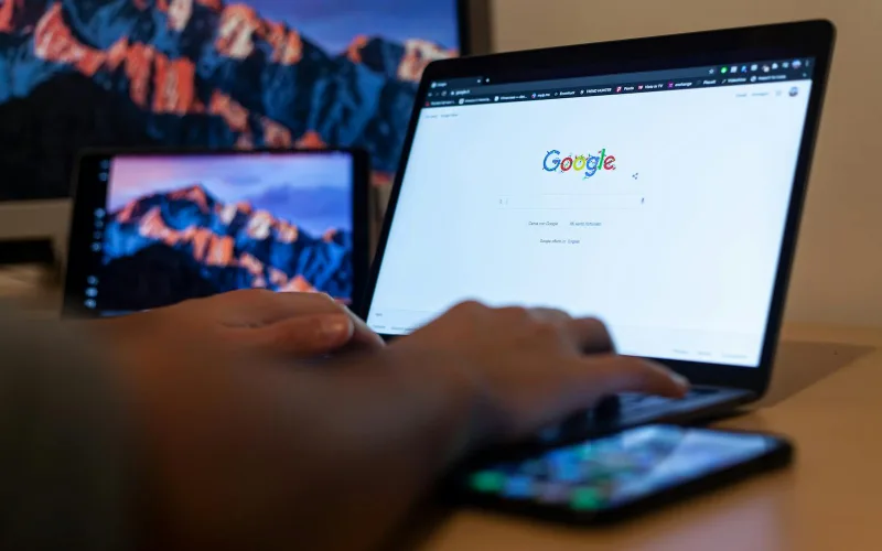 Hands typing on a laptop with Google on screen, in a remote work setup in Milan, Italy.
