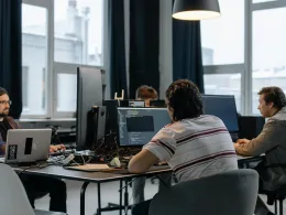 Team of developers working together on computers in a modern tech office.