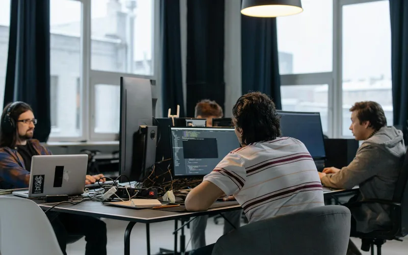Team of developers working together on computers in a modern tech office.